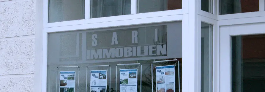 Schaufenster mit dem Schriftzug Sari Immobilien und Exposés